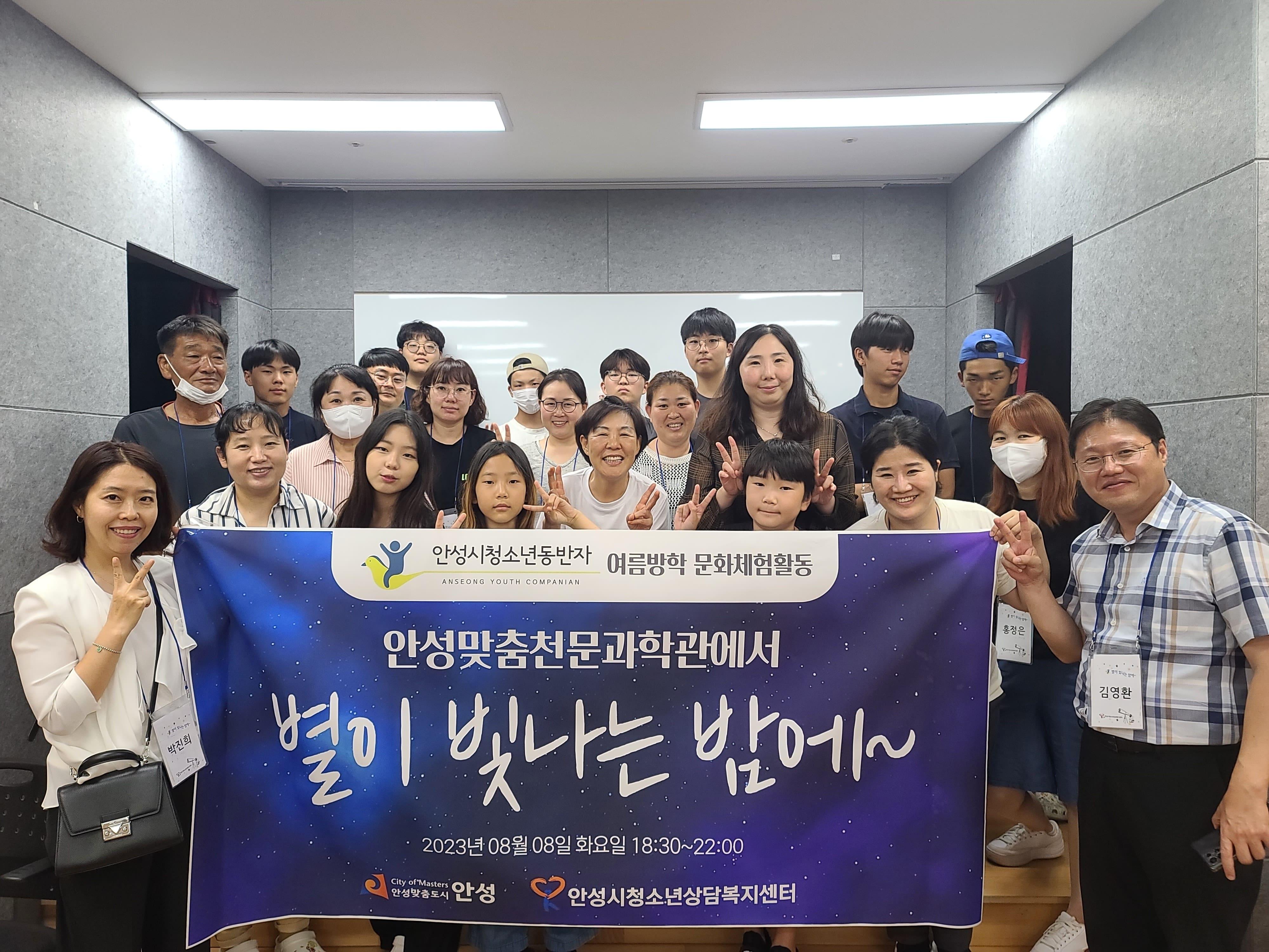 성인 남녀 및 학생들이 모여서 현수막 들고 단체로 사진찍는 모습